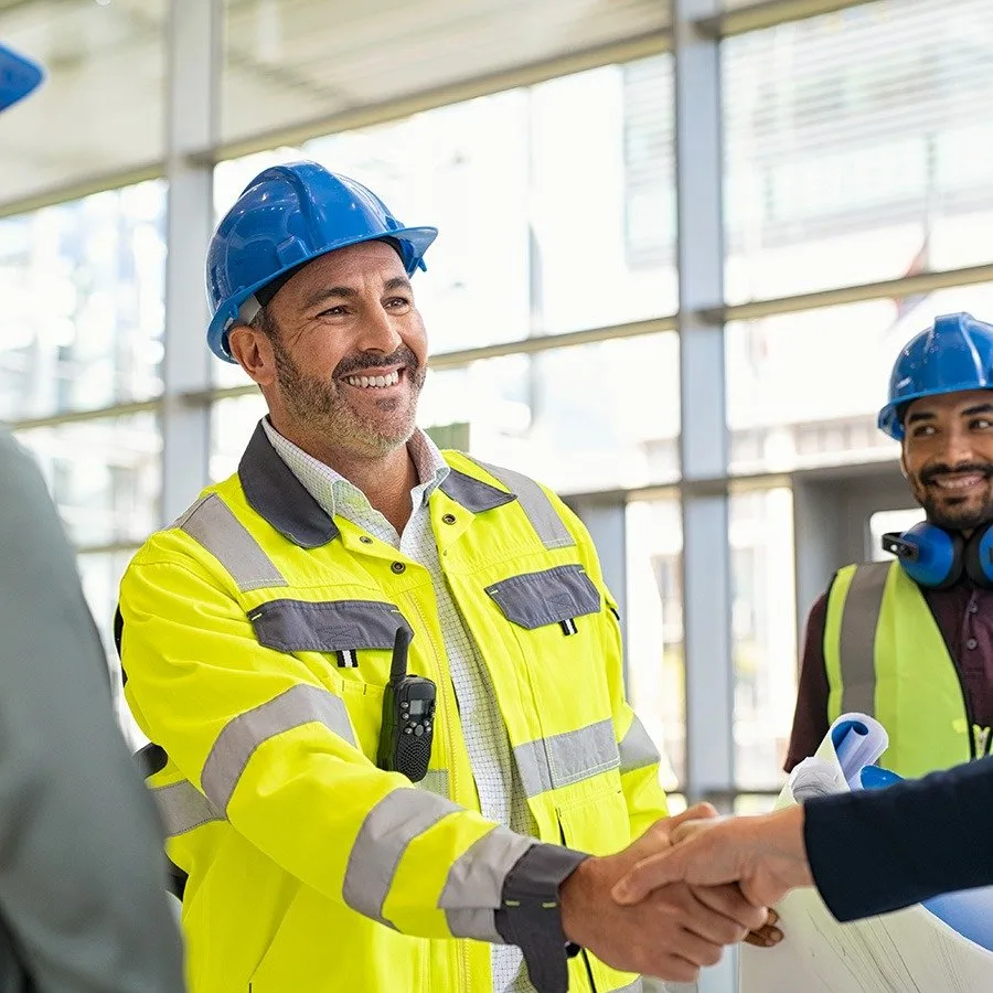 Site engineers in safety vests shaking hands at a construction site in Bhopal