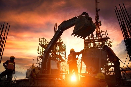 Construction site with excavator and workers at sunset